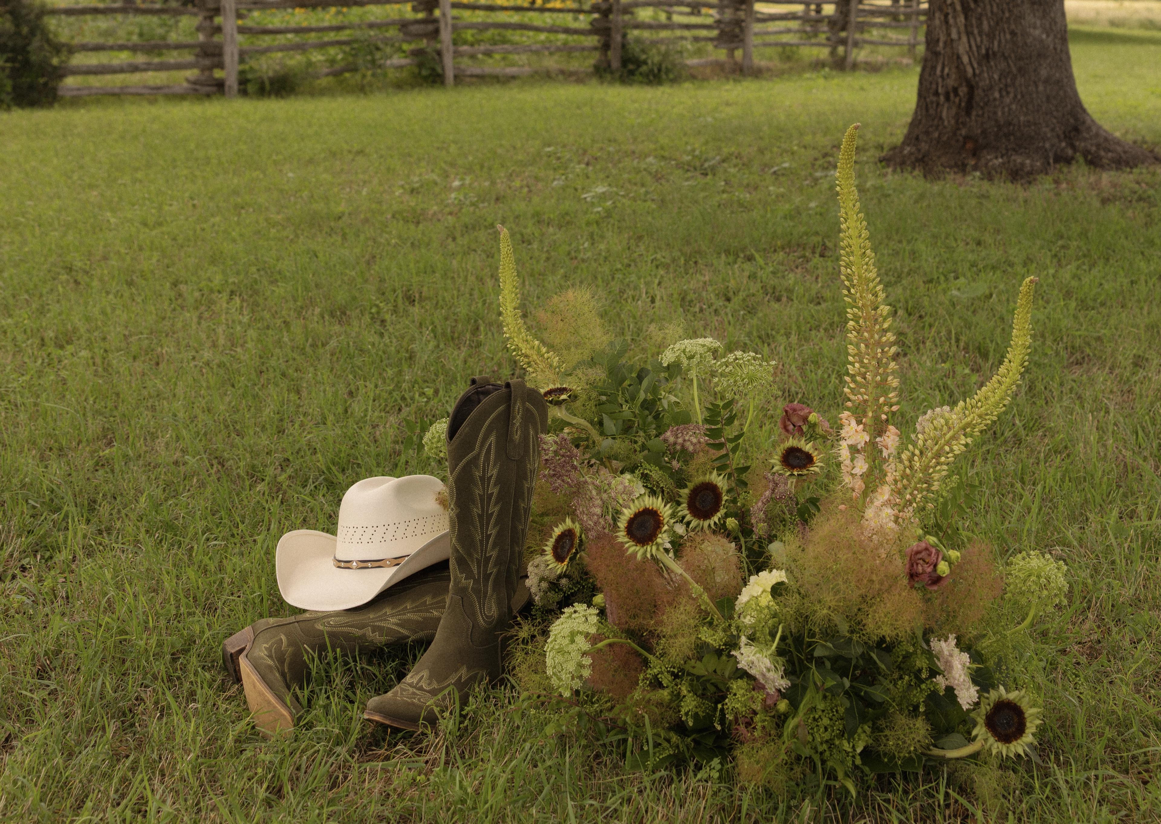 Garden-inspired flowers with sunflowers, cowboy boots, and a cream cowboy hat on the grass