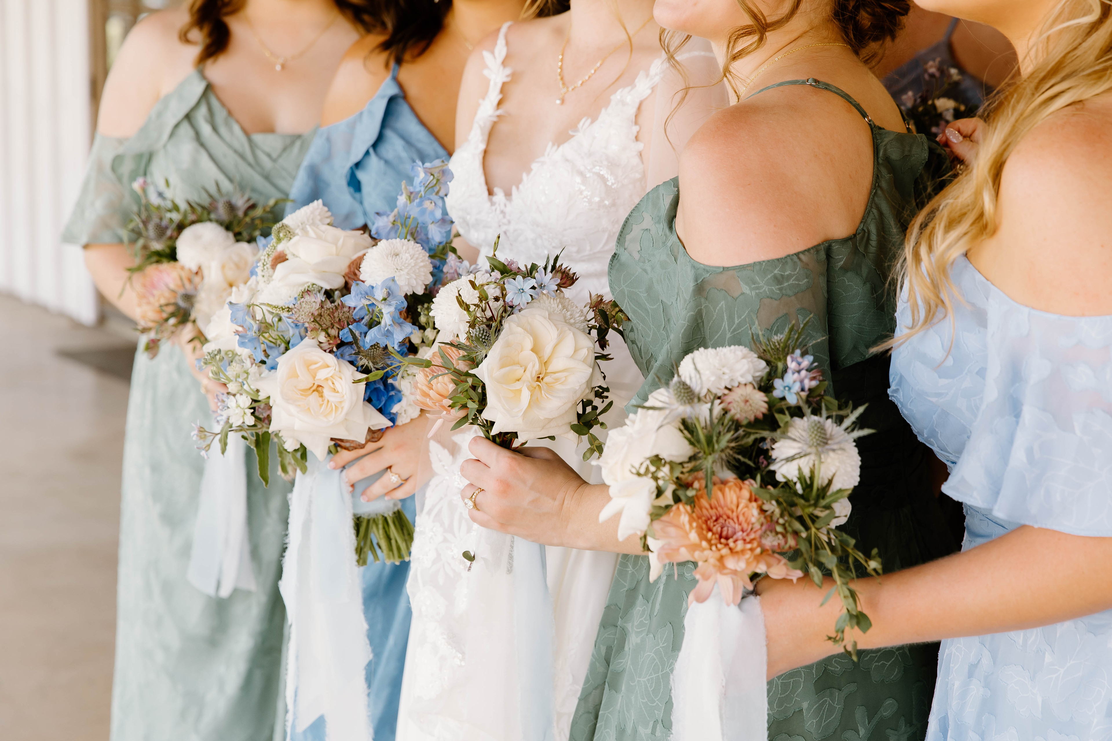 Brooke and her bridesmaids holding bouquets of white, blue, and peach flowers