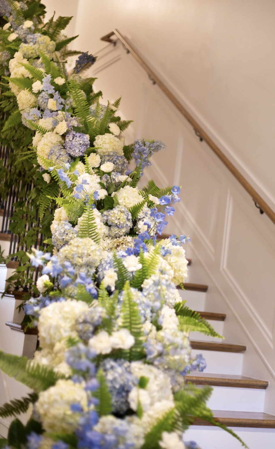 Blue and white flowers with lush ferns cascading along the Tri Delt staircase